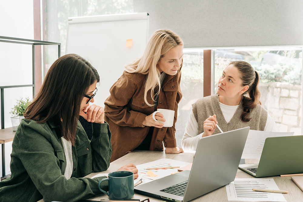 Business colleagues discussing over computer at desk in office